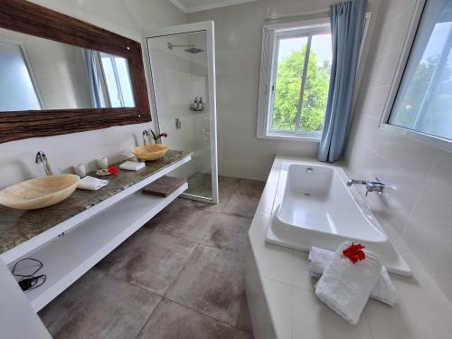 ein weißes Badezimmer mit Waschbecken und Badewanne in der Unterkunft House on a rock in Anse aux Pins