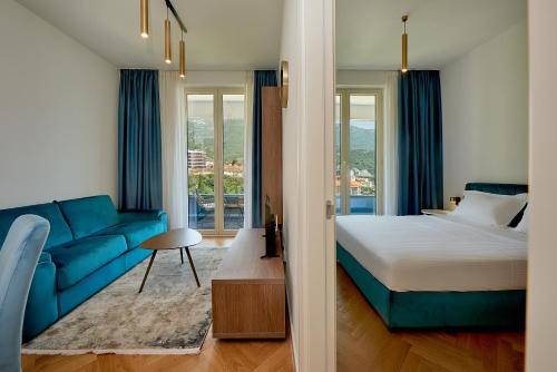 une chambre avec un lit et un canapé bleu dans l'établissement Skyline resort CG, à Budva