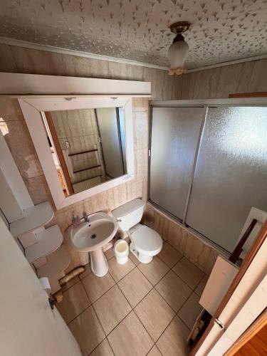 a bathroom with a sink and a toilet and a mirror at Hostal Parediso in Punta Arenas
