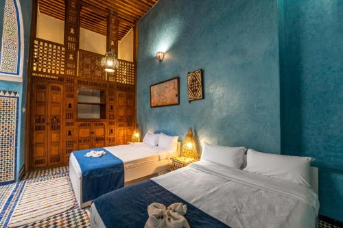 a bedroom with two beds and a blue wall at Dar Na in Station Bab Ftouh