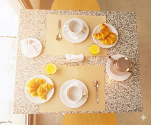 Una mesa con platos y tazas de café y croissants. en RM Campana Hotel, en Campana