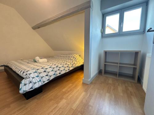 ein Schlafzimmer mit einem Bett im Dachgeschoss mit einem Fenster in der Unterkunft La maison d'Audrey - maison au pied du Hahenberg - au calme - parking gratuit in Châtenois