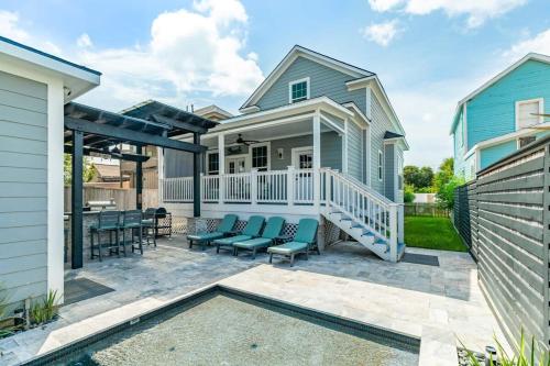 a patio with blue chairs and a house at Exudes the Posh Life Heated Pool Fireplace & Stunning in Galveston