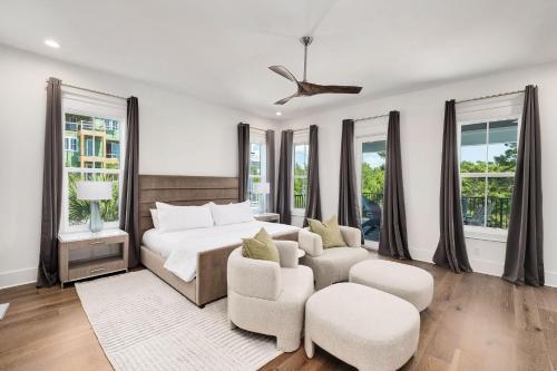 a bedroom with a bed and chairs and windows at Oz by The Sea in Inlet Beach