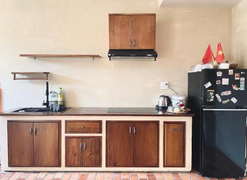 a kitchen with wooden cabinets and a black refrigerator at Biển house in Ấp Khánh Phước (1)