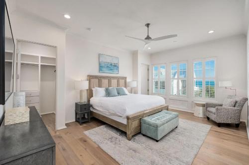 a white bedroom with a bed and a chair at Dogwood Lookout in Seagrove Beach