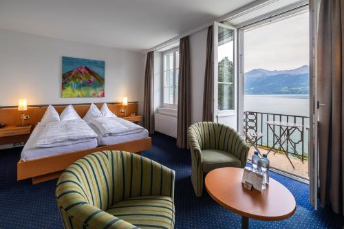 a hotel room with a bed and two chairs at Parkhotel Gunten – Beach & Spa in Gunten