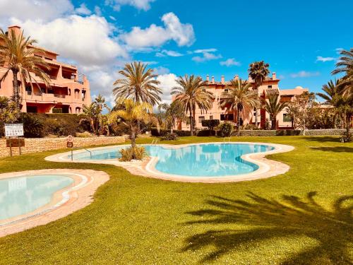 - une piscine bordée de palmiers et un bâtiment dans l'établissement Cosy & Moderne appartement vue mer, à Finestrat