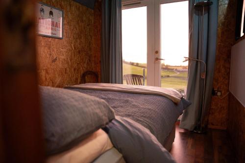a bedroom with a bed and a large window at Unique Glamping Experience - The Horse Box 