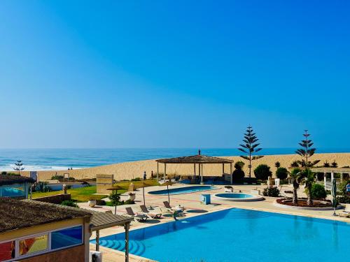 a resort with a swimming pool and the beach at Ocean Dunes House in Mirleft