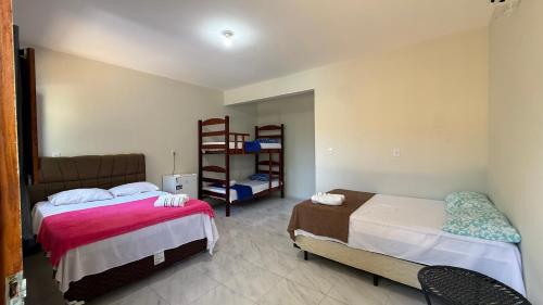 a bedroom with two beds and a book shelf at Pousada Linhares in Canoa Quebrada
