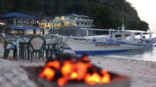 a group of chairs and a boat on the beach at Scandi Divers in Puerto Galera