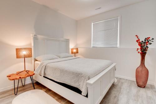 a white bedroom with a bed and a vase with flowers at Cozy Lakeview Retreat in Kettle Valley in Kelowna