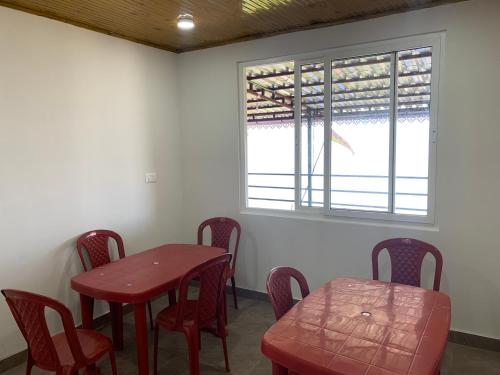 a red table and chairs in a room with a window at Begonia Homestay Darjeeling in Darjeeling