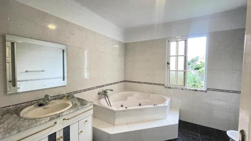 une salle de bain blanche avec une baignoire et un lavabo dans l'établissement Casa Borboleta, à Arco da Calheta