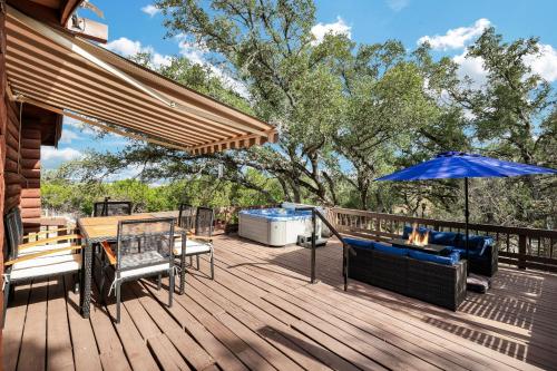 eine Terrasse mit einem Tisch und einem blauen Sonnenschirm in der Unterkunft Canyon Lake Haven Cabin Hot Tub Yard Bbq Fire Pit in Canyon Lake