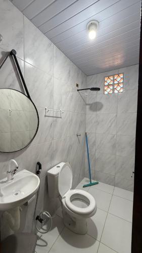 a white bathroom with a toilet and a sink at Pousada Linhares in Canoa Quebrada