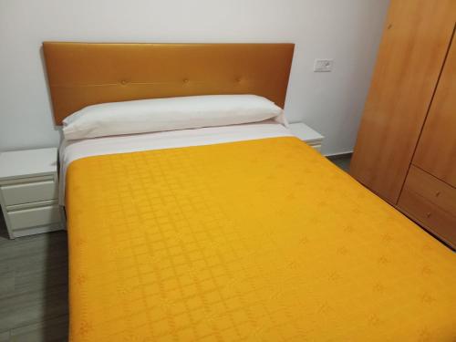 a bedroom with a yellow bed with a wooden headboard at La Ferroviaria -Suite 1 Dormitorio Con Salón más Baño Privado - Balcón - 2º Sin Ascensor- in Zaragoza