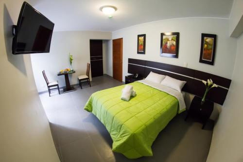 a bedroom with a green bed and a television at Mariategui Hotel & Suites in Lima