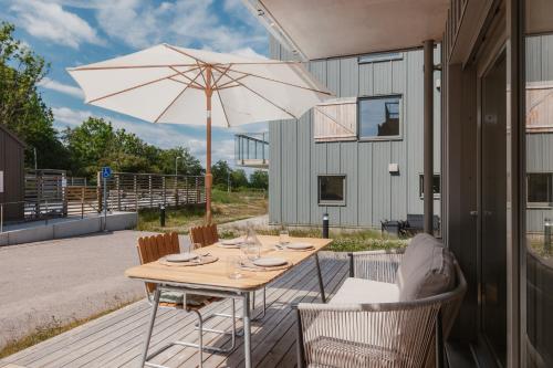 a wooden table with an umbrella on a patio at Luxury Living at Ekerum Öland Heated Pool, Golf & Sea! in Borgholm