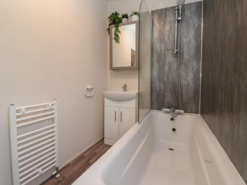 a bathroom with a large white tub and a mirror at Meadows Park 4 in Hull