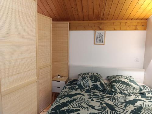 a bedroom with a bed and a wooden ceiling at La Maison au bord de l'Ain in Charnoz