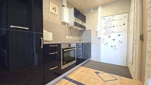 een keuken met zwarte kasten en een witte koelkast bij Leuchtturm in Schönberg