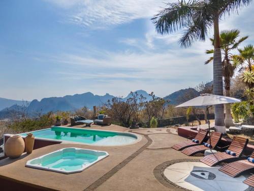 a pool with chairs and an umbrella and mountains at Private 5-Bedroom Compound with Pool Tepoztlán Retreat in Tepoztlán