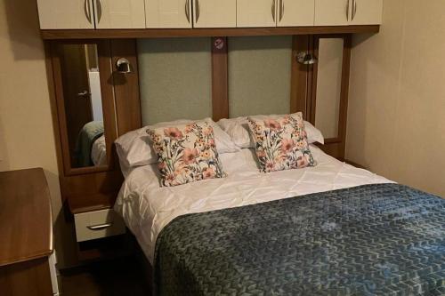 a bedroom with a bed with pillows and a mirror at Lodge - Sleeps 6 - Parking - Garden in Cockermouth