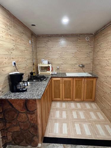 a kitchen with wooden cabinets and a stone wall at Le Relax, Dellys 