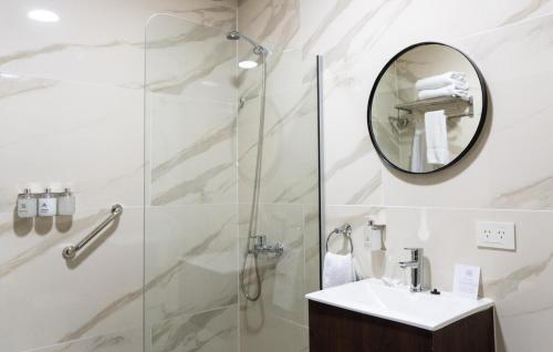 a bathroom with a shower and a sink and a mirror at RM Campana Hotel in Campana