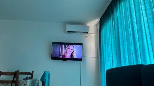 a television on a wall next to a blue curtain at Apartamente me qera tale plazh lezhë in Lezhë