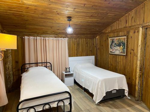 two beds in a room with wooden walls at CHALÉS DO VÔ LÉRIO/TORRES-RS in Torres