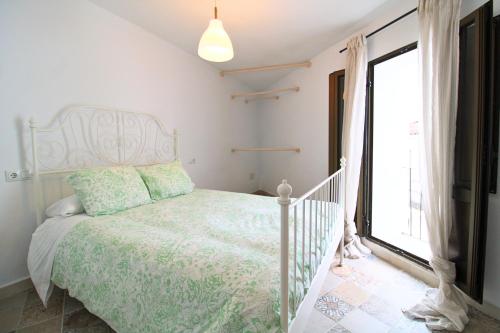 a white bedroom with a bed and a window at Ca' Magüi in Jabugo