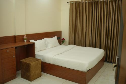 a bedroom with a bed and a desk and curtains at Joen homes apartment in Alwaye