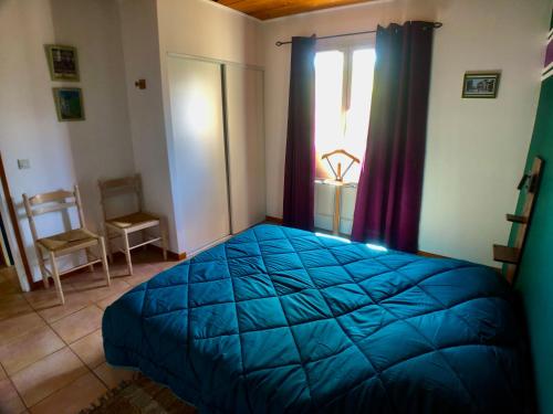 a bedroom with a blue bed and a window at Les Cades in Labeaume