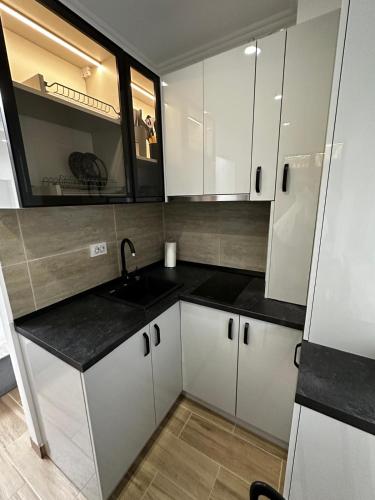 a small kitchen with white cabinets and a sink at Apollo Studio 7 - Parking in Dudu