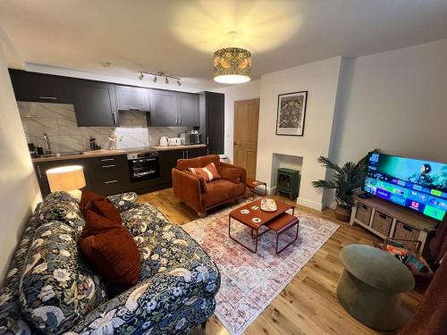 a living room with a couch and a table and a television at Old Betting Shop for 3 & Furry Friend in Hayfield