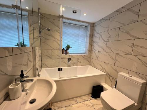 a bathroom with a tub and a toilet and a sink at Old Betting Shop for 3 & Furry Friend in Hayfield