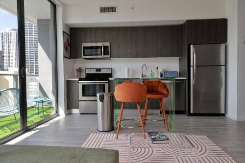 a kitchen with stainless steel appliances and an orange chair at Downtown Luxe Studio in Miami