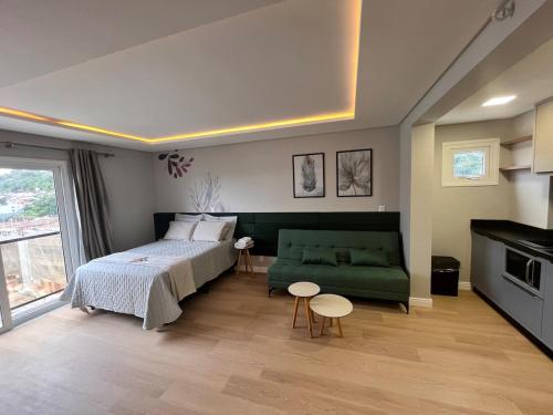 ein Schlafzimmer mit einem Bett und einem grünen Sofa in der Unterkunft Loft Super aconchegante a 50mt da Vila Germânica com estacionamento gratuito in Blumenau