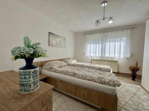 ein Schlafzimmer mit einem Bett und einer Vase mit Blumen in der Unterkunft Apartment in Ilidza in Sarajevo