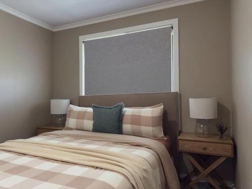 a bedroom with a bed with two night stands and a window at Delamere Farm Stay in Delamere