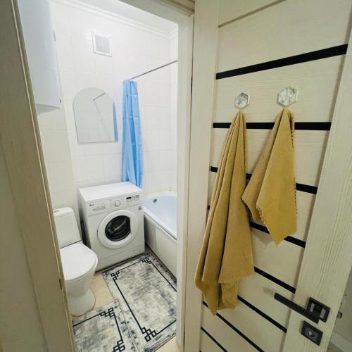 a bathroom with a toilet and a washing machine at 1ком КВ по суточно, по часовой in Koshi