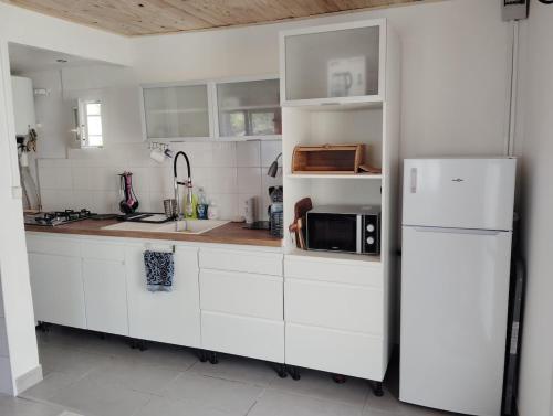 a kitchen with white cabinets and a white refrigerator at petite maison sans vis a vis in Thoirette