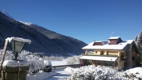 a building covered in snow with a mountain in the background at Hotel Veduta dell'Adamello in Temù