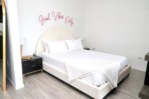 a bedroom with a white bed with a sign that reads good wake up at Downtown Miami Slice of Paradise in Miami