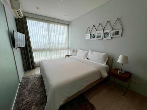 a bedroom with a large white bed and a window at Stay with me by Veranda Resident in Na Jomtien