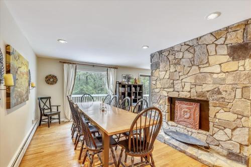 a dining room with a table and a stone fireplace at Spruce Pond Haven in Stowe