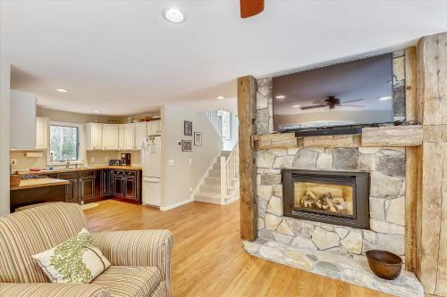a living room with a stone fireplace with a flat screen tv at Spruce Pond Haven in Stowe